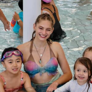 A mermaid performer in the pool with children