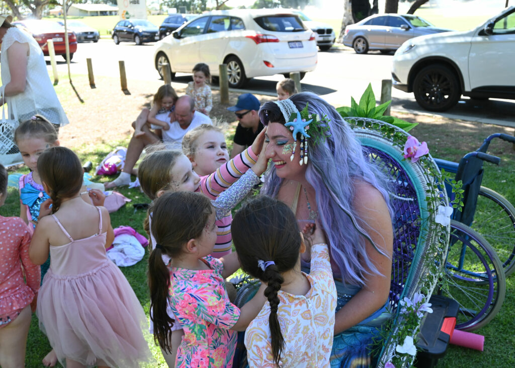 A mermaid performer surrounded by children at a birthday party