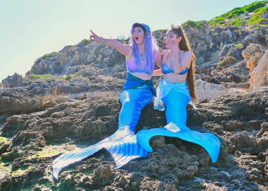 2 mermaid performers on the rocks
