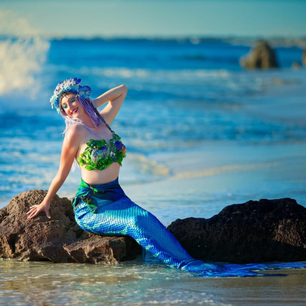 A mermaid performer posing on the rocks