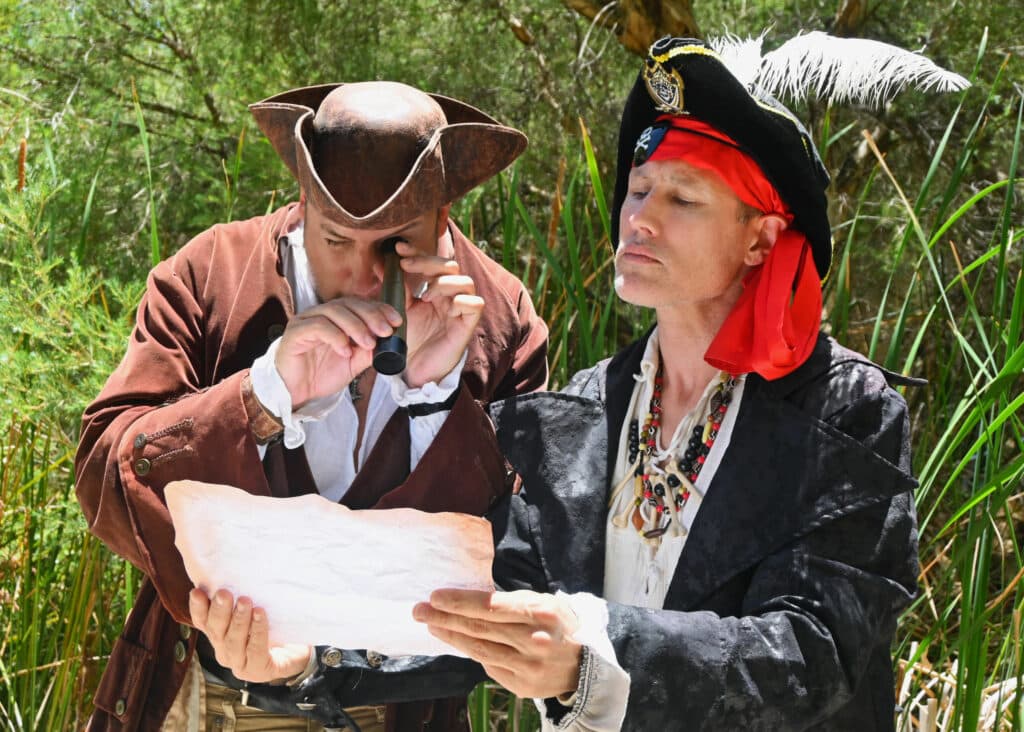 Two pirate performers looking at a treasure map at a children's party