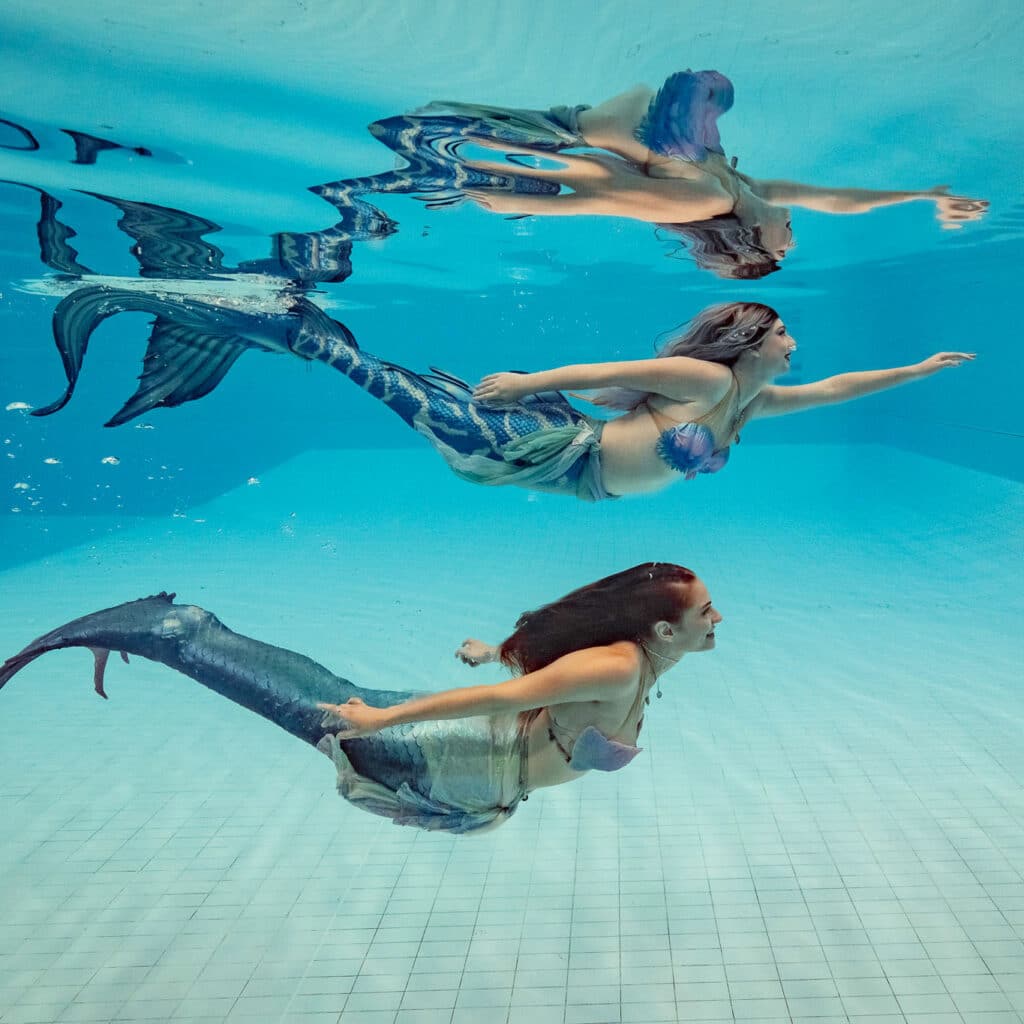 2 mermaid performers swimming underwater