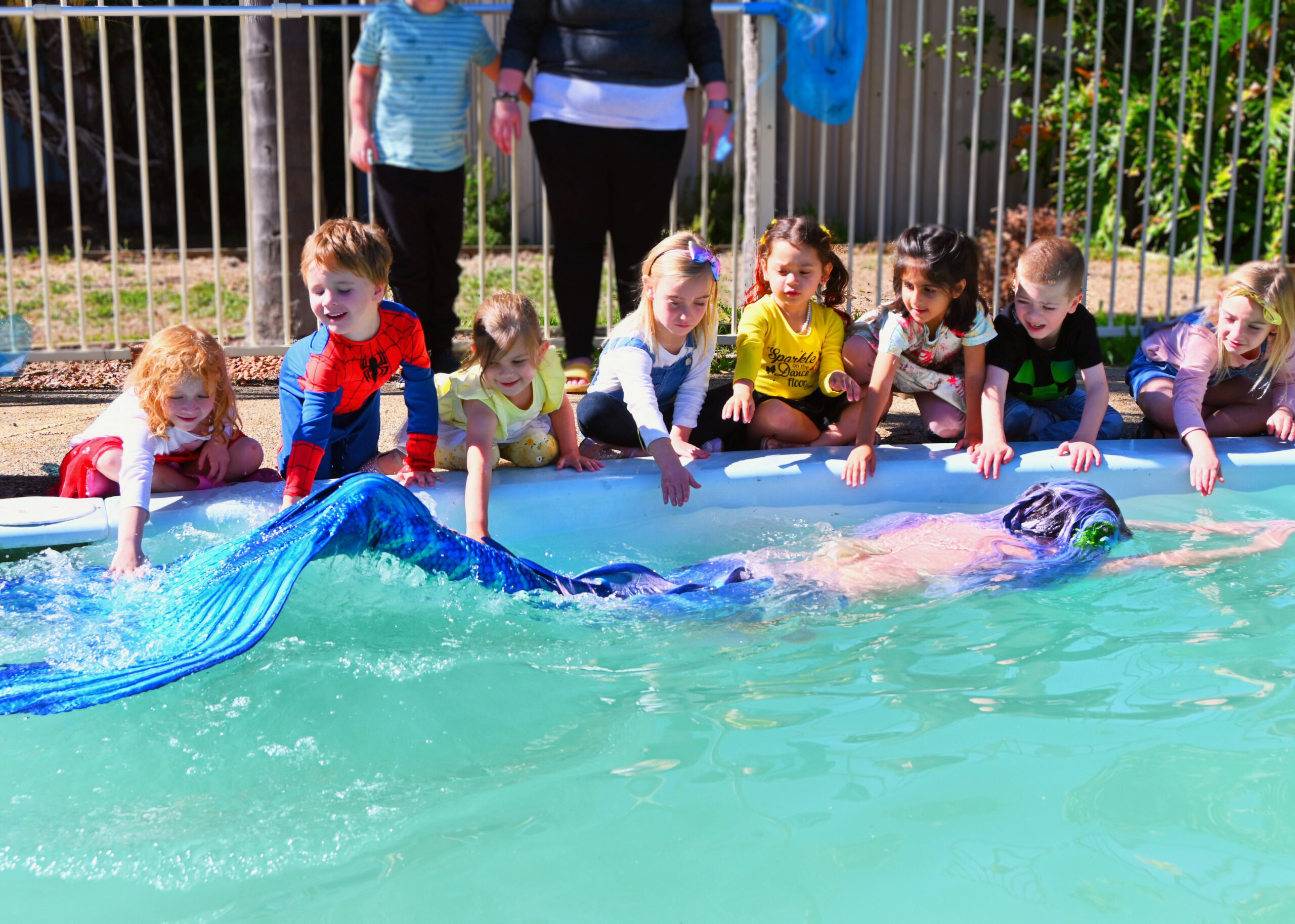 A mermaid performer swimming in a pool at a children's party